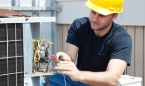 Electrician wearing a yellow hard hat working on electrical wiring of an air conditioning unit, illustrating professional electrical services for residential and commercial needs in Miami.